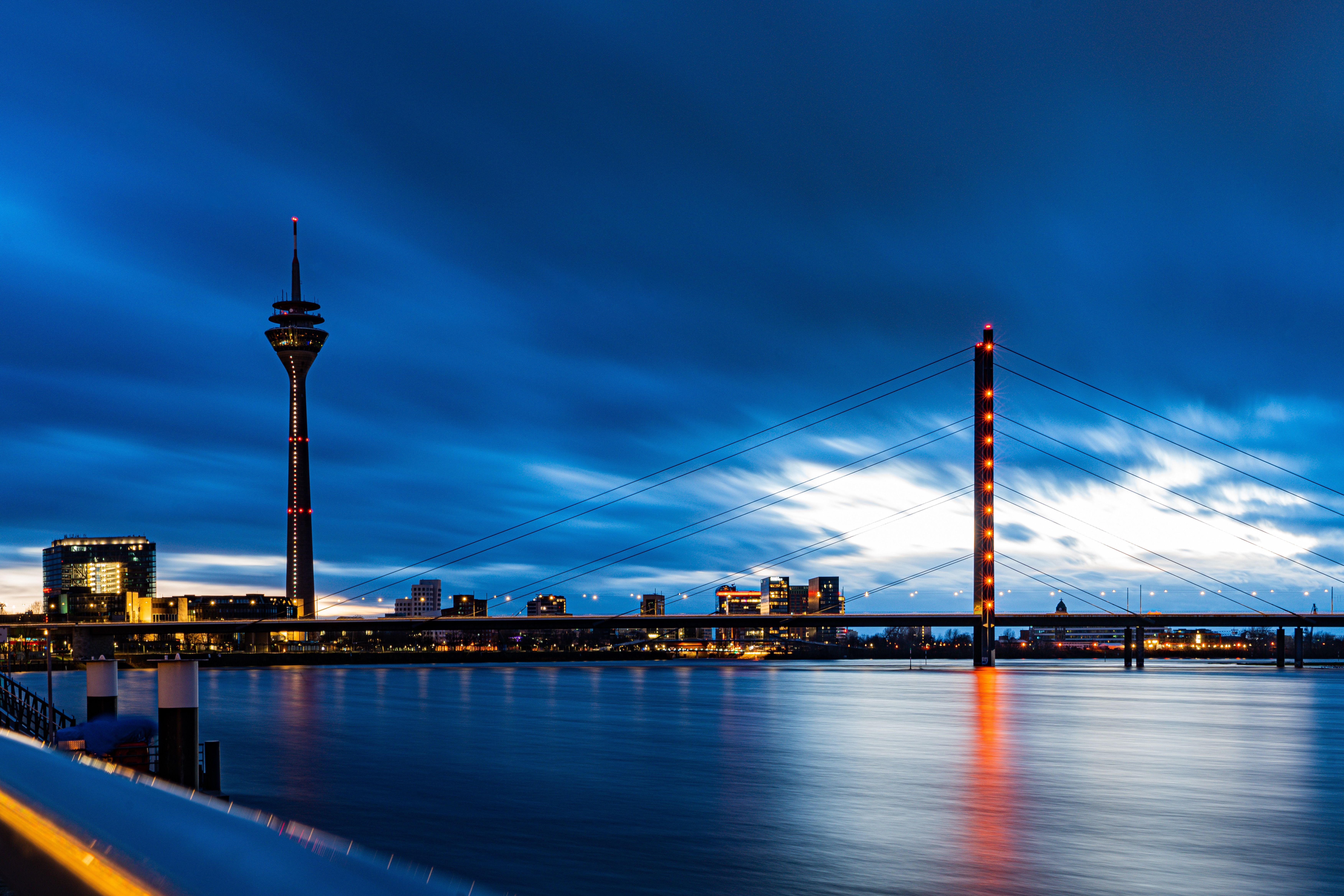 Düsseldorf at night, with the illuminated Rheinturm and bridge lights reflected on the Rhine.